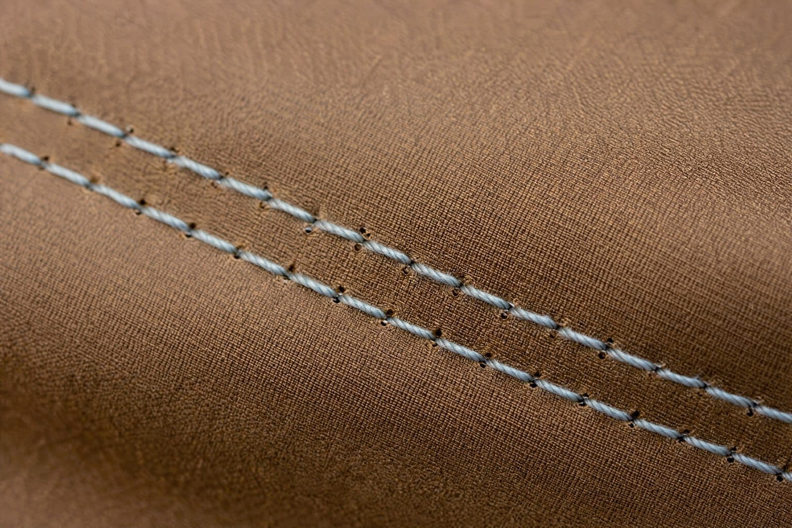 A plain double-row stitched seam with no tape, the needle perforations clearly visible as a line of small open holes.